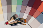 A selection of different colours on paper alongside paint brushes