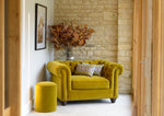 A mustard yellow chair in a light an airy room. 