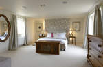 a bed, mirror and chest of drawers in a bedroom. 