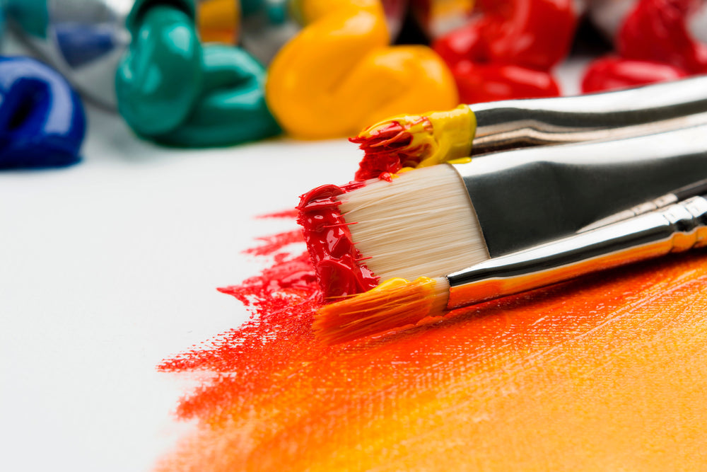Paintbrushes with red, yellow and orange paint on them. 