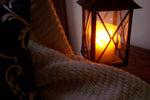 A lit candle in a lantern-style holder.
