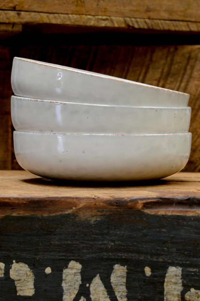 A stack of small Broste Nordic Sand shallow bowl.